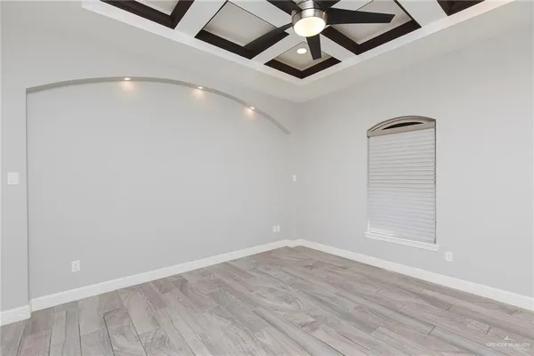 an empty room with a ceiling fan and wooden floor