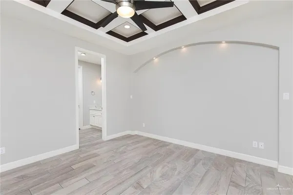 an empty room with wooden floor and ceiling fan