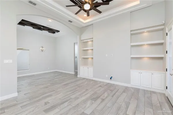 a view of an empty room with a window and wooden floor
