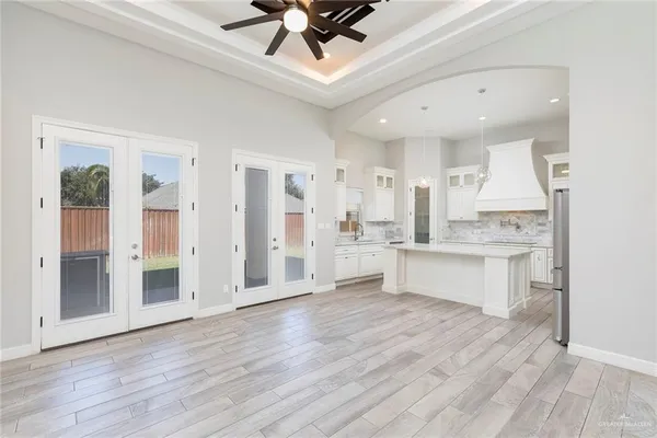 a large white kitchen with a refrigerator a sink dishwasher a stove and a dining table with wooden floor