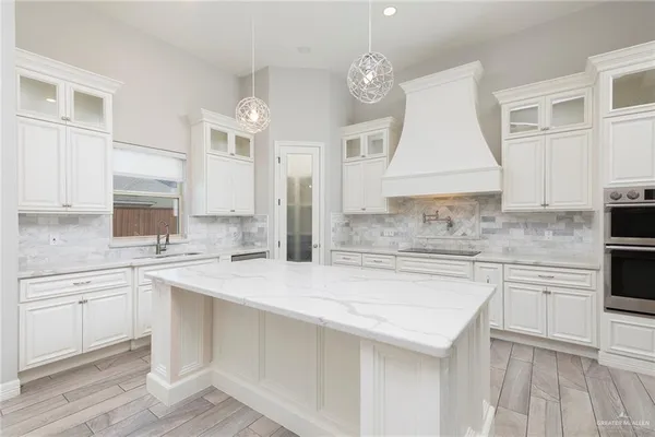 a kitchen with a sink dishwasher a stove and white cabinets with wooden floor