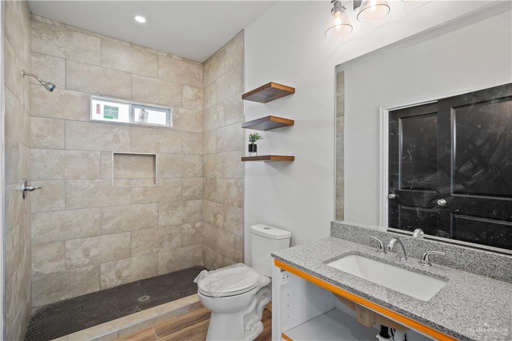 2317 Tuscany Road Weslaco, TX 78596 - Photo 6 of 13 a bathroom with a granite countertop sink a toilet a mirror and shower
