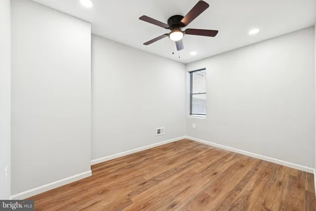 an empty room with wooden floor and ceiling fan