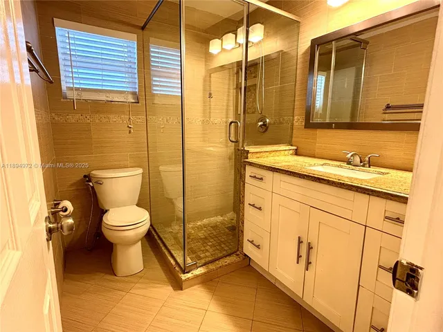 a bathroom with a granite countertop toilet sink and mirror