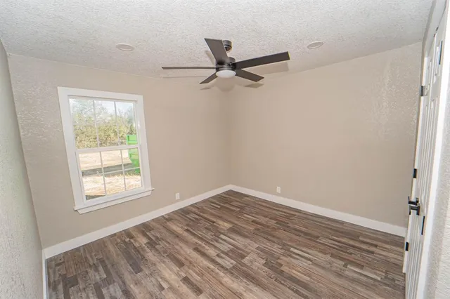 an empty room with windows and fan