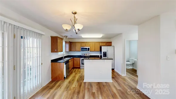a kitchen with stainless steel appliances granite countertop a refrigerator a sink dishwasher a stove and white countertops with wooden floor