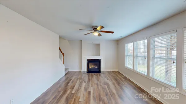 a view of an empty room with a window and wooden floor
