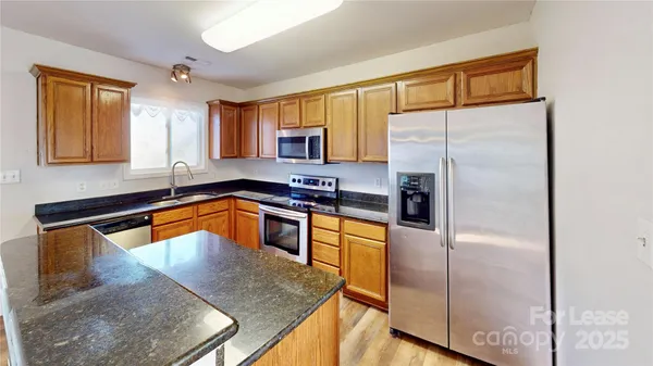 a kitchen with stainless steel appliances granite countertop a refrigerator a sink and white cabinets