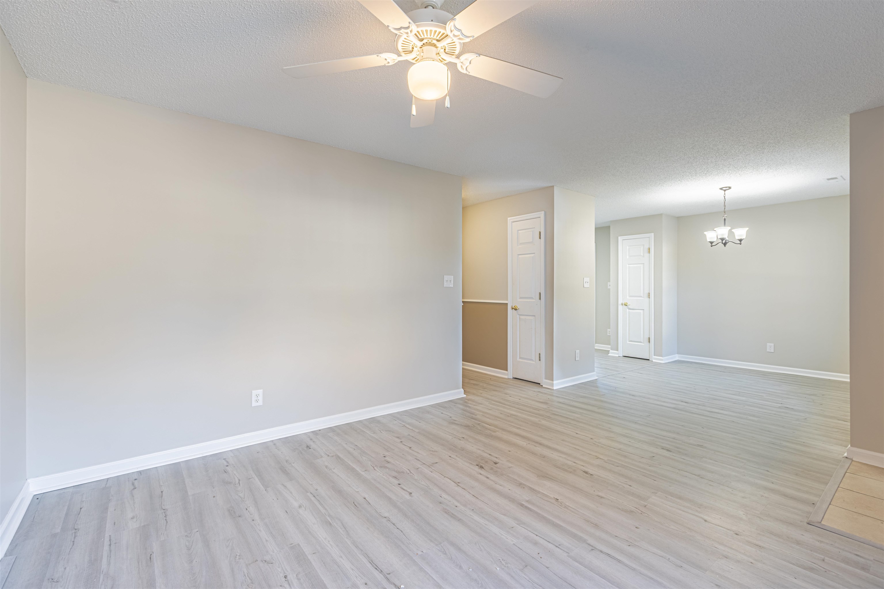 1001 Mistletoe Court Myrtle Beach, SC 29579 - Photo 6 of 28 Spare room featuring light wood-style flooring, a textured ceiling, a chandelier, and ceiling fan