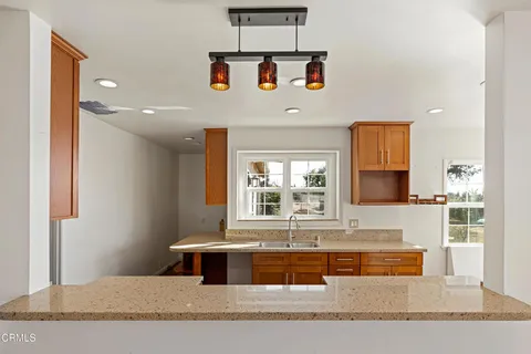 a kitchen with stainless steel appliances granite countertop a sink dishwasher a stove and a refrigerator with wooden floor