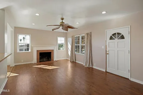 an empty room with windows fireplace and wooden floor