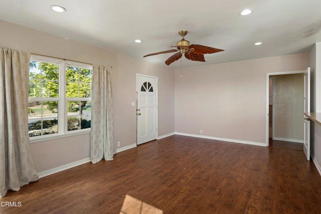 an empty room with wooden floor chandelier fan and windows