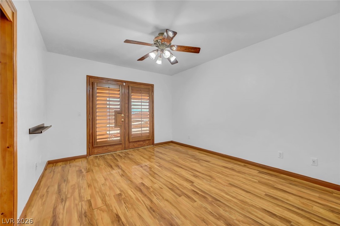 640 North Racetrack Road Henderson, NV 89015 - Photo 34 of 65 Hardwood-style flooring extends across this room, featuring French doors with privacy shutters and a ceiling fan.