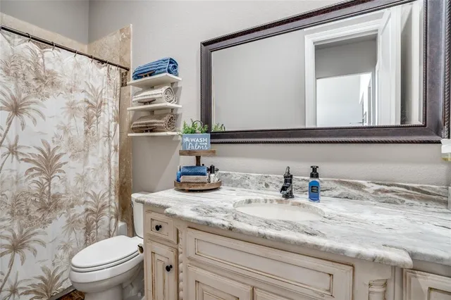a bathroom with a granite countertop sink a toilet and a mirror
