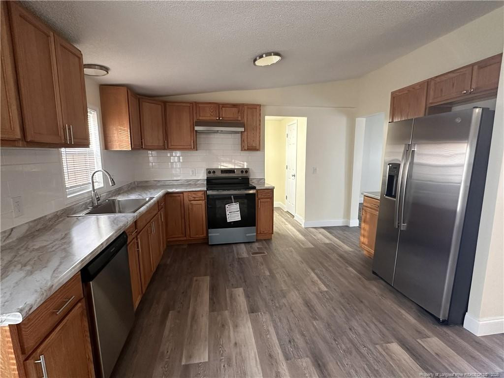 542 Red Oak Farm Road Tar Heel, NC 28392 - Photo 5 of 15 a kitchen with stainless steel appliances granite countertop a refrigerator a sink dishwasher a stove top oven a refrigerator with wooden floors and cabinets