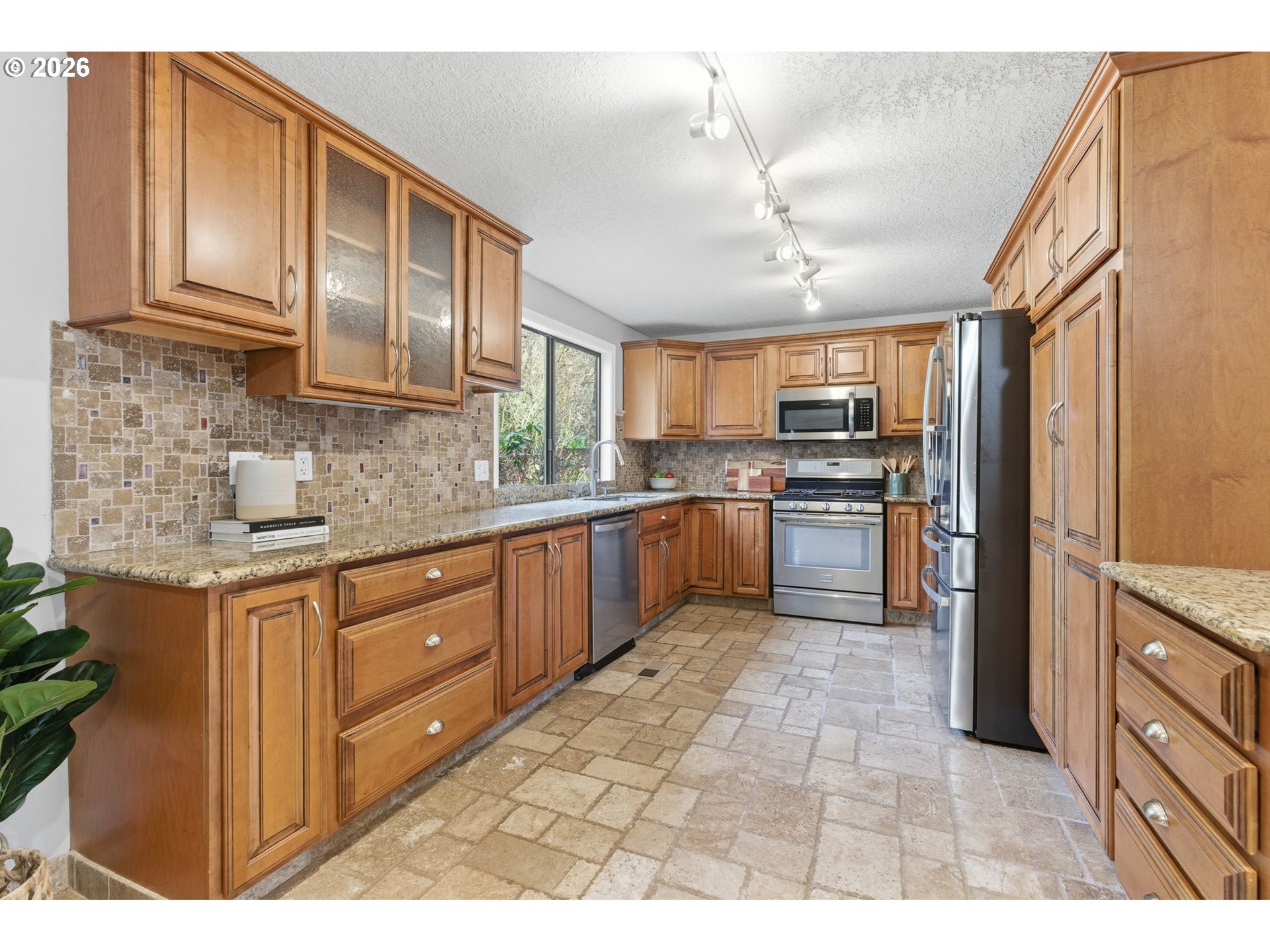 5585 Northwest Peregrine Place Portland, OR 97229 - Photo 15 of 47 a kitchen with stainless steel appliances granite countertop a refrigerator a sink dishwasher a stove with wooden cabinets and floor