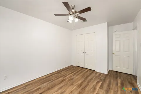 an empty room with wooden floor and ceiling fan