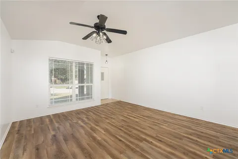 a view of empty room with wooden floor and ceiling fan
