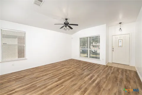a view of empty room with wooden floor and fan