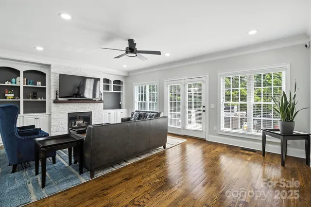 a living room with furniture a fireplace a flat screen tv and wooden floor