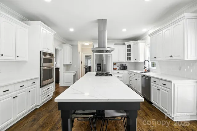 a kitchen with stainless steel appliances kitchen island granite countertop a kitchen island hardwood floor sink and stove