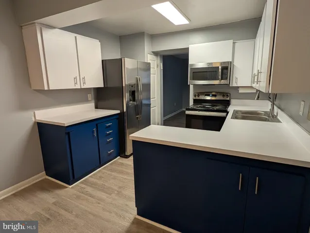 a kitchen with stainless steel appliances a sink dishwasher stove refrigerator and microwave with wooden floor