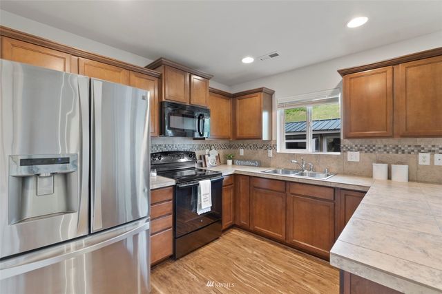 a kitchen with stainless steel appliances granite countertop a refrigerator sink and stove
