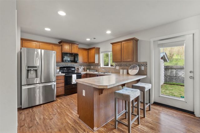 a kitchen with stainless steel appliances granite countertop a refrigerator a sink a stove a dining table and chairs