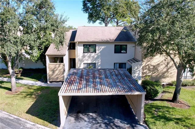 a view of a house with potted plants and a large tree