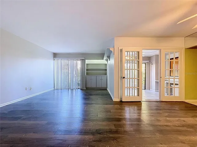 an empty room with wooden floor fan and windows
