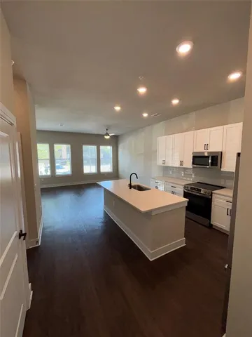 a living room with couches and kitchen view with wooden floor