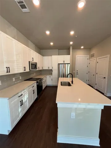 a large white kitchen with wooden floors and white stainless steel appliances