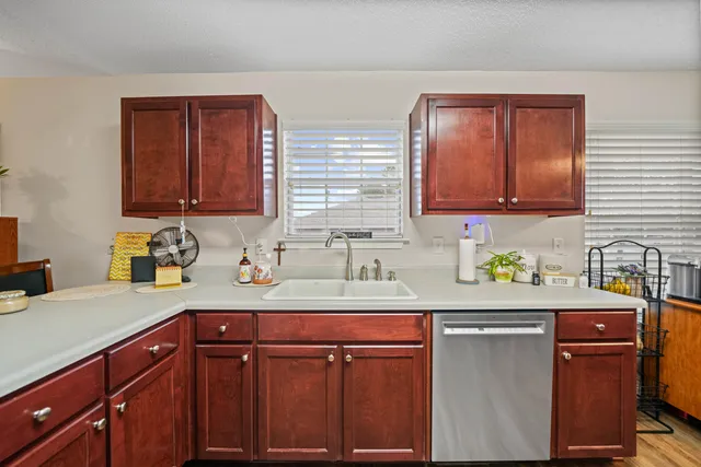 a kitchen with granite countertop wooden cabinets a sink and dishwasher