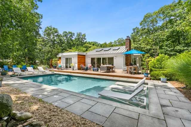 a view of a house with pool lawn chairs and a barbeque