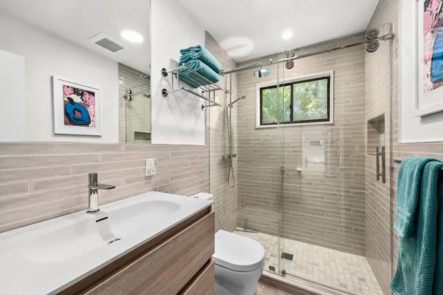 a bathroom with a sink a toilet a shower and a mirror