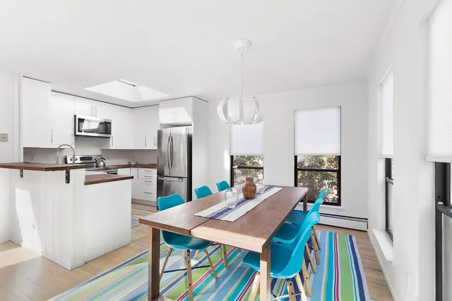 a kitchen with stainless steel appliances kitchen island granite countertop a refrigerator a stove and white cabinets with wooden floor