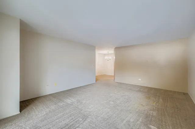 a view of an empty room and chandelier fan