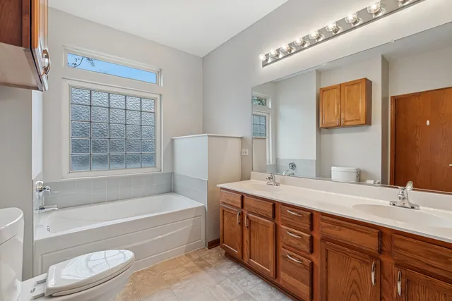 a bathroom with a granite countertop bathtub shower sink vanity and toilet