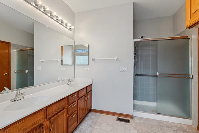 a bathroom with a double vanity sink a large mirror and shower