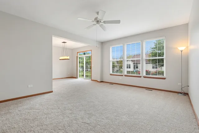 an empty room with windows and ceiling fan