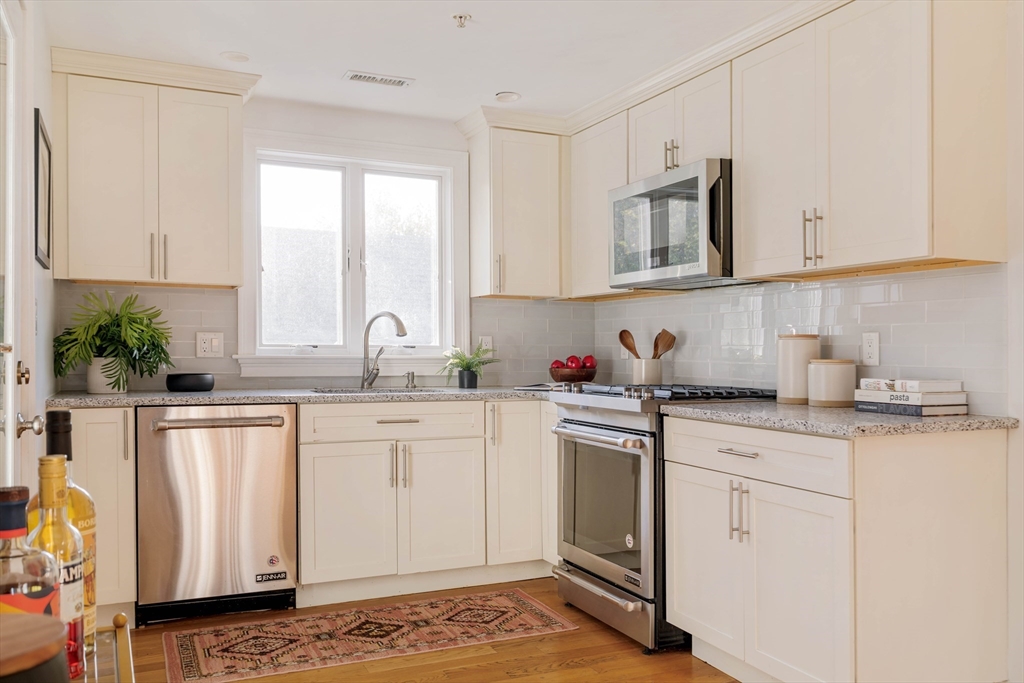 59 Berkeley Street, Unit 3 Somerville, MA 02143 - Photo 7 of 18 a kitchen with granite countertop white cabinets and white appliances