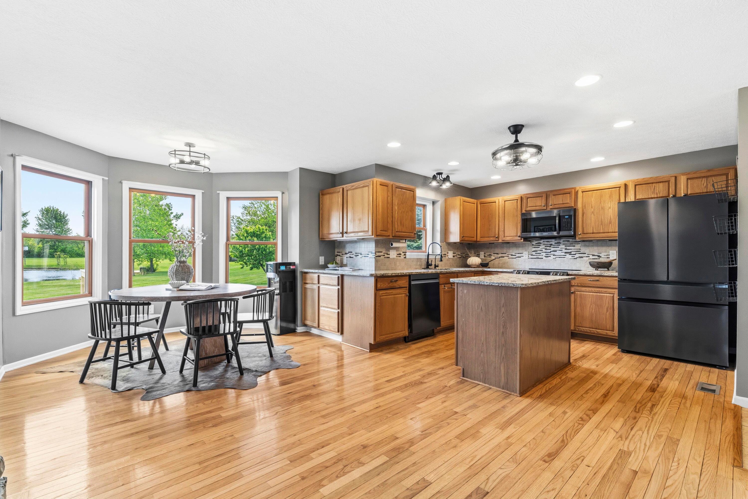 8507 Benner Road Johnstown, OH 43031 - Photo 17 of 69 Large Kitchen with hardwood floors and Dining Area with bay window & double fireplace! Granite countertops, island, NEW Black Stainless Steel Appliances, including an induction oven! NEW Reverse Osmosis to sink/Fridge/Brio+