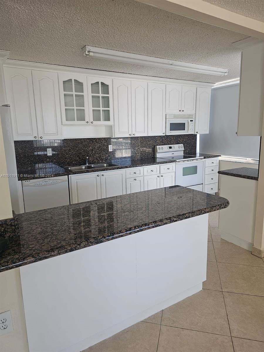 a large kitchen with granite countertop a sink and a stove
