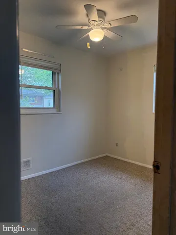 an empty room with a window and a fan