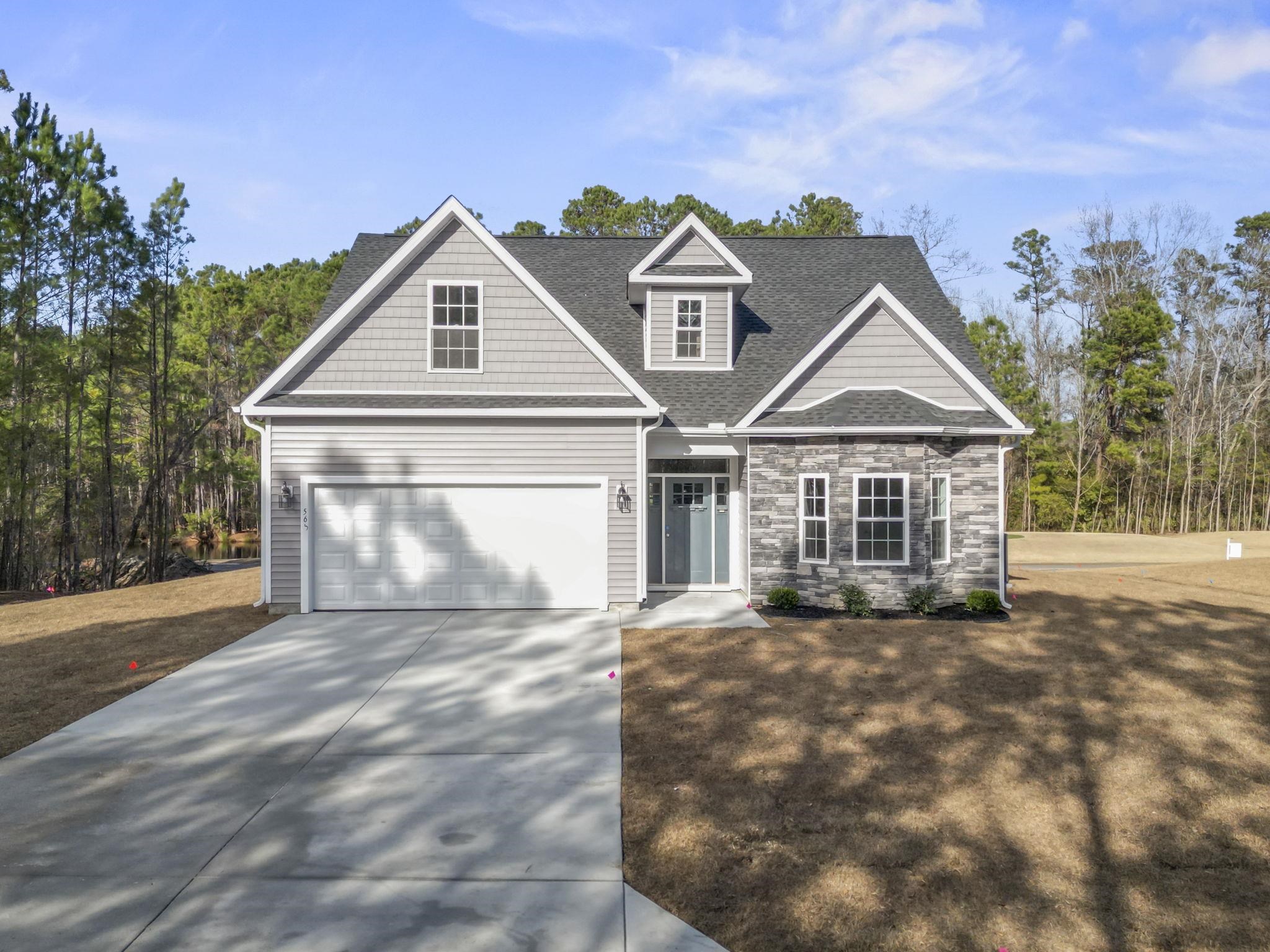View of front of home with concrete driveway, a garage, a shingled roof, and stone siding