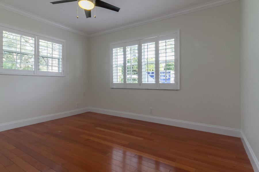 1120 Southwest 20th Street Boca Raton, FL 33486 - Photo 26 of 53 an empty room with wooden floor chandelier fan and windows