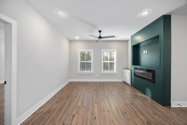 a view of an empty room with a window and wooden floor