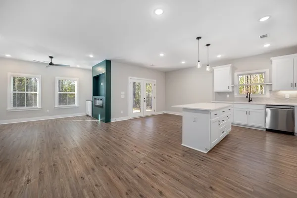 a large kitchen with stainless steel appliances a large counter top a sink a refrigerator and a window