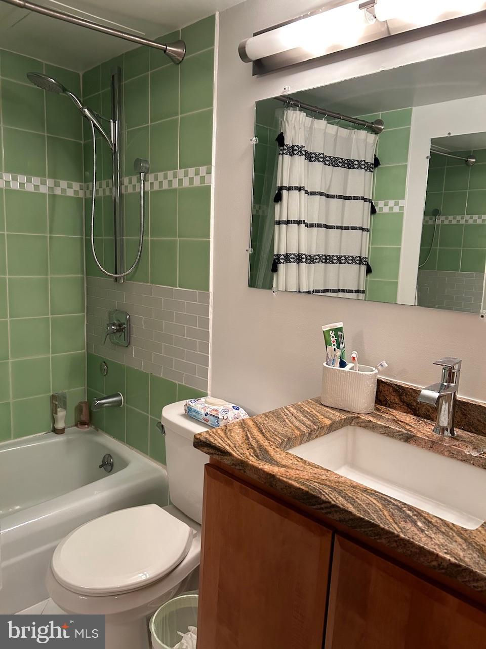 4242 East-West Highway, Unit 708 Chevy Chase, MD 20815 - Photo 9 of 12 a bathroom with a granite countertop sink a toilet a mirror and bathtub