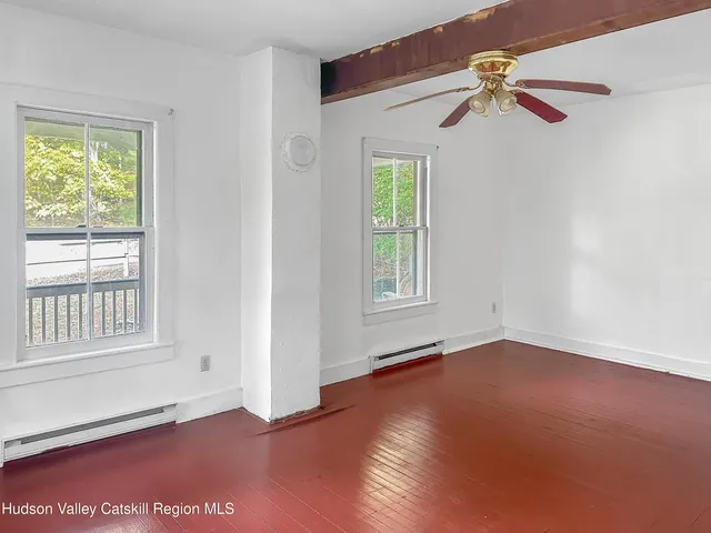 an empty room with windows and fan